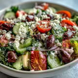 Freshly prepared Greek Salad Bowl topped with juicy tomatoes, crunchy cucumbers, and tangy red onion.
