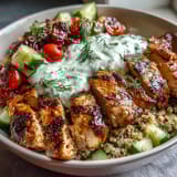 Bright cherry tomatoes and Kalamata olives add color to a Greek Chicken Power Bowl beside a generous dollop of cool tzatziki.