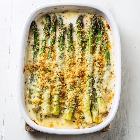 Bright green tender asparagus in a creamy white cheese sauce under a golden baked breadcrumb crust, served as a comforting spring casserole.