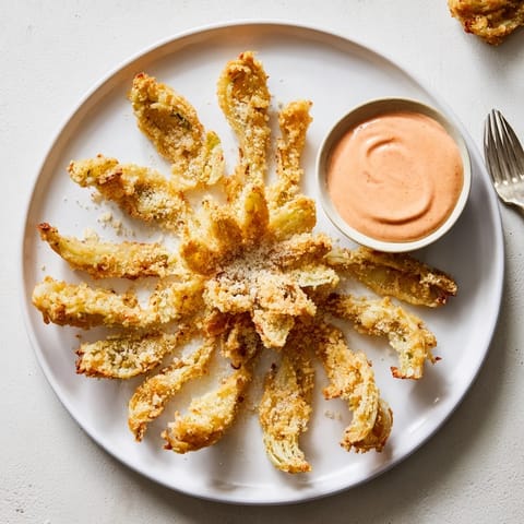 A close-up of golden-fried Onion Petals with Spicy Dipping Sauce, revealing crispy batter and tender sweet onion layers.