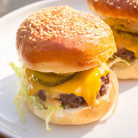 Twelve juicy sliders topped with pickles and onions on a wooden platter, perfect for a game-day spread.