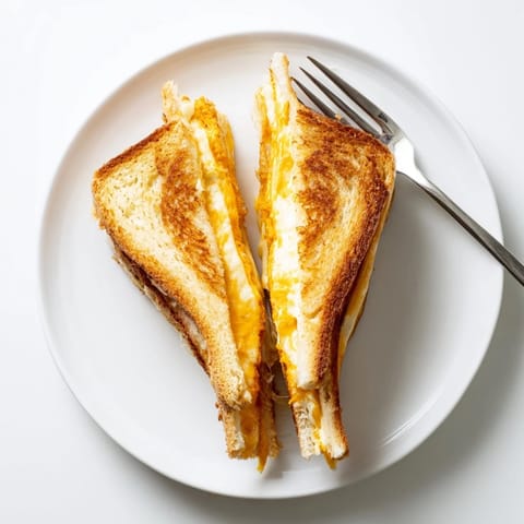 A close-up of a Triple Cheese Sourdough Grilled Cheese sandwich, oozing melted mozzarella and sharp cheddar from golden, crispy sourdough slices.