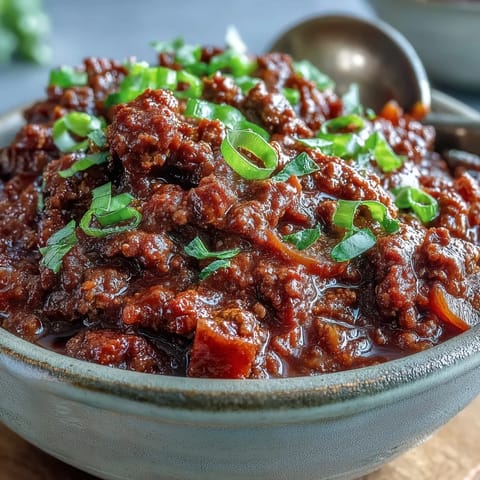 Slow Cooker Chili simmers with ground beef, beans, and spices, bubbling rich and aromatic. Garnish with cheese and sour cream.