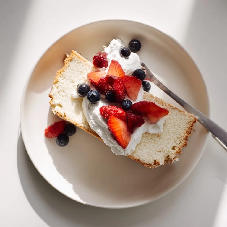Freshly baked Angel Food Cake in a tube pan, inverted to cool for a light, fluffy crumb and perfect height.