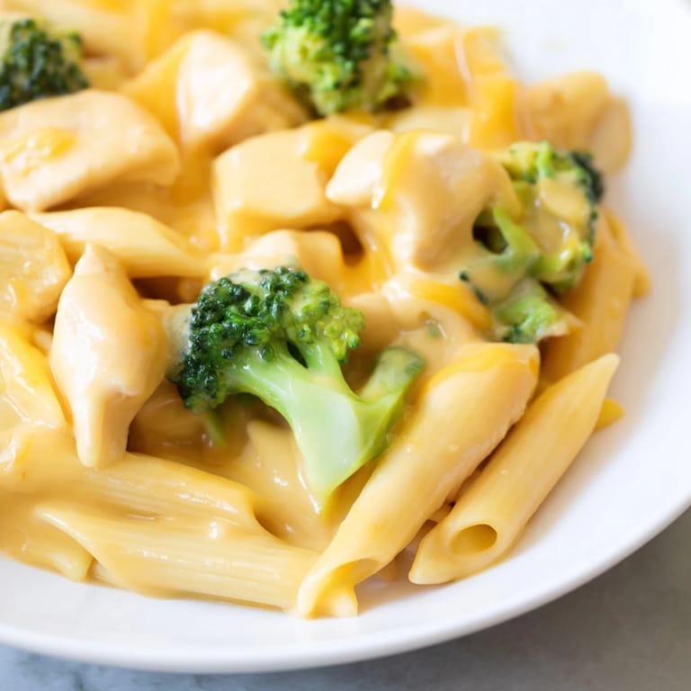 Golden, cheesy Chicken Broccoli Cheddar Pasta twirled on a fork, showcasing juicy chicken, steamed broccoli, and a luscious, comforting sauce for a family-friendly meal.