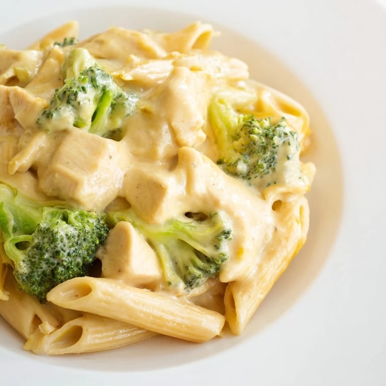 Freshly cooked Chicken Broccoli Cheddar Pasta plated on a white dish, garnished with extra cheddar, ready to be enjoyed with a side of garlic bread.