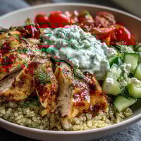 Juicy lemon-herb grilled chicken slices sit atop fluffy quinoa with crisp cucumbers and tomatoes in this Greek Chicken Power Bowl.